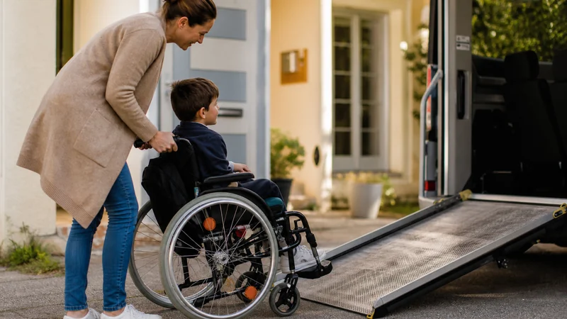 Un parent aide un enfant en fauteuil roulant à monter dans un véhicule aménagé équipé d'une rampe